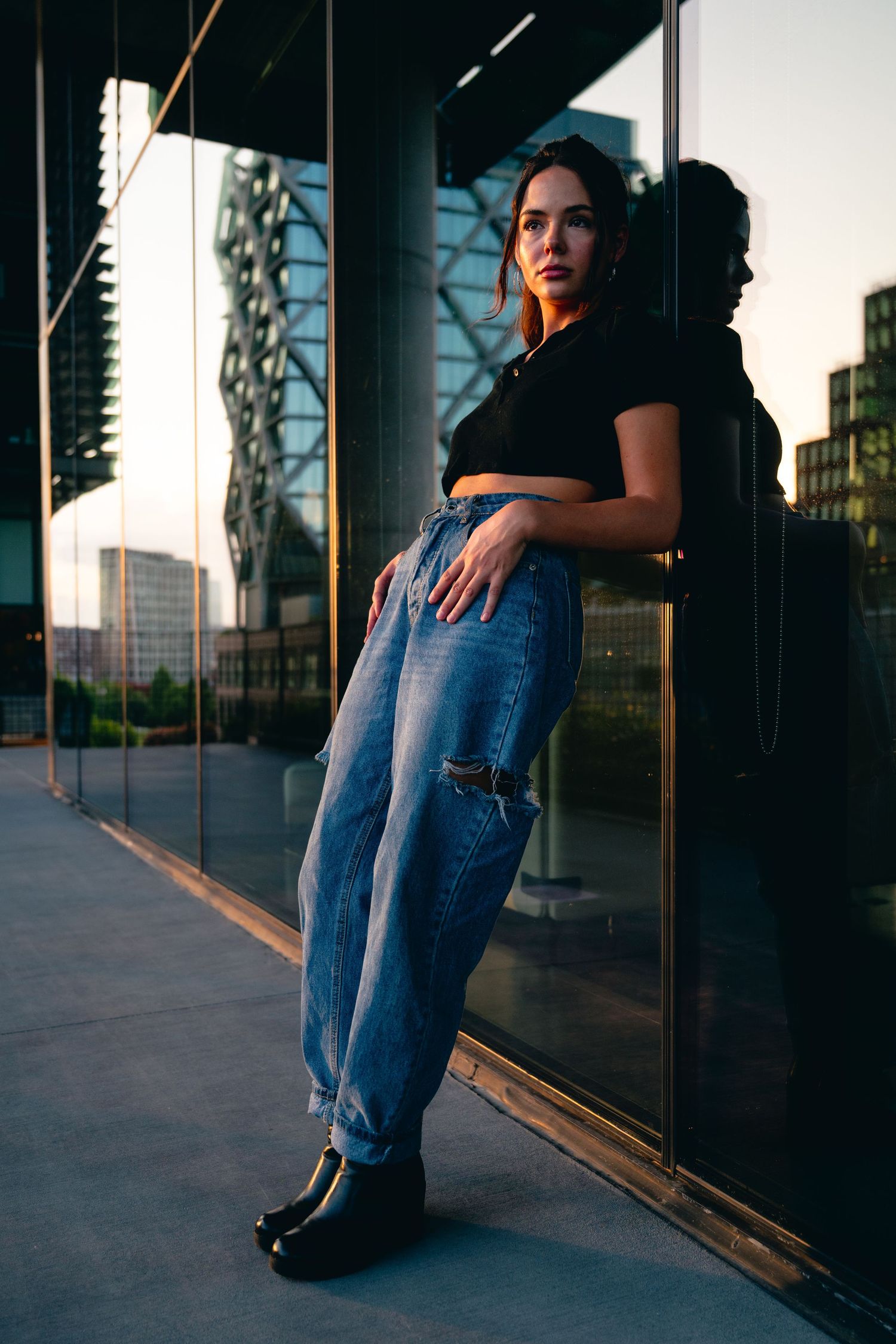 Urban fashion photography against modern building exterior with glass panels.