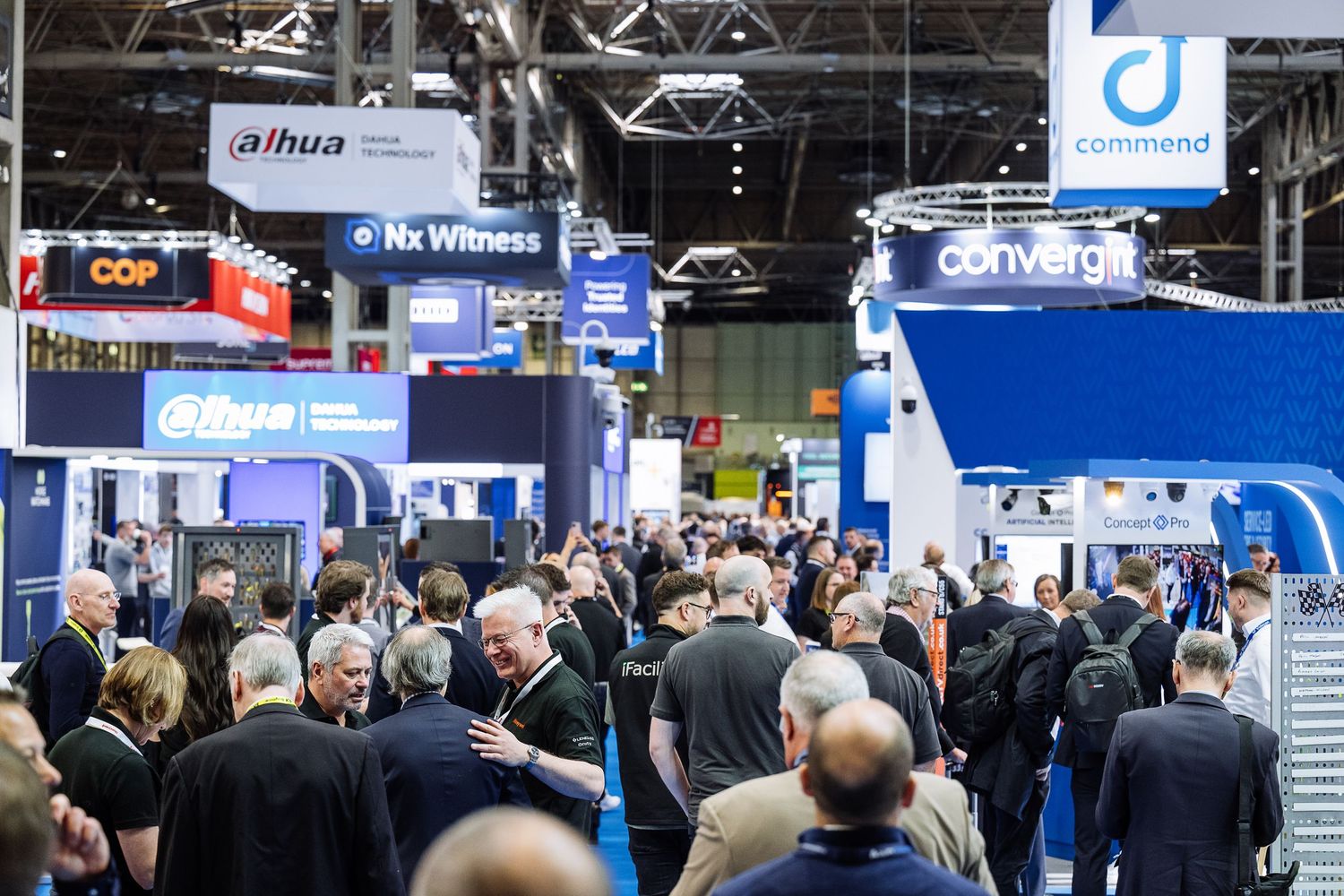 Crowded technology trade show floor with vendor booths and digital displays.