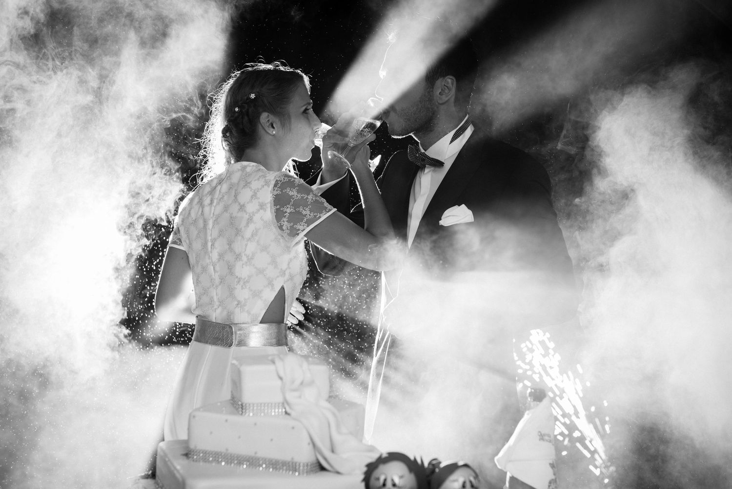 Dramatic black and white photo of wedding entertainment through atmospheric smoke and lights.