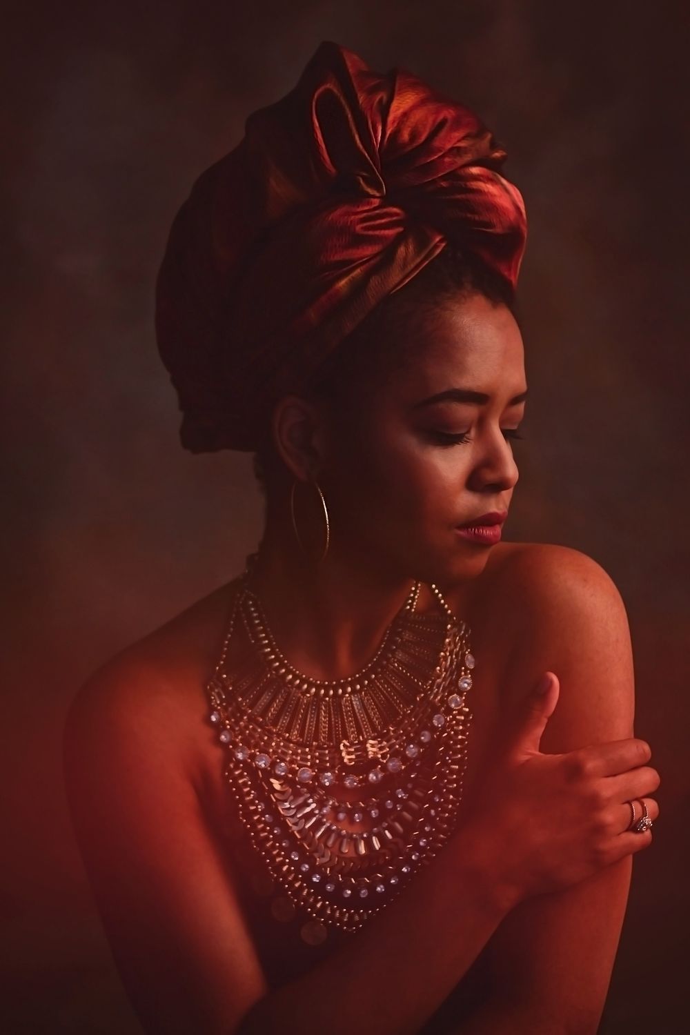 Artistic portrait series in warm red tones featuring an elegant diamond necklace against bare shoulders.