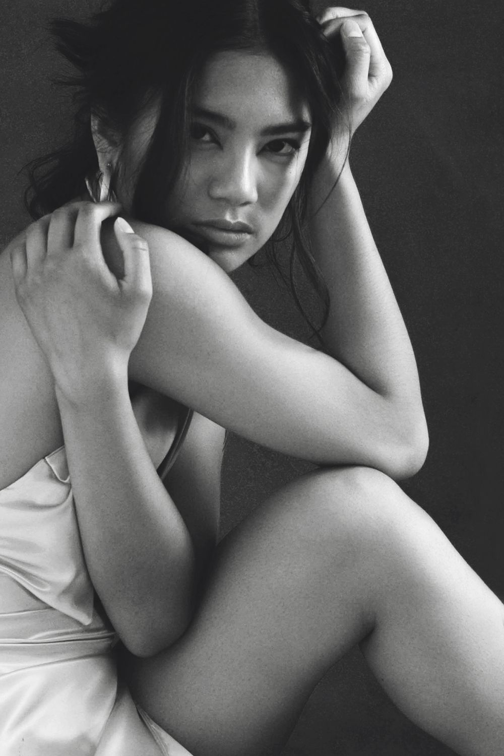 Black and white artistic portrait of a model in white fabric posing with dramatic shadows and composition.