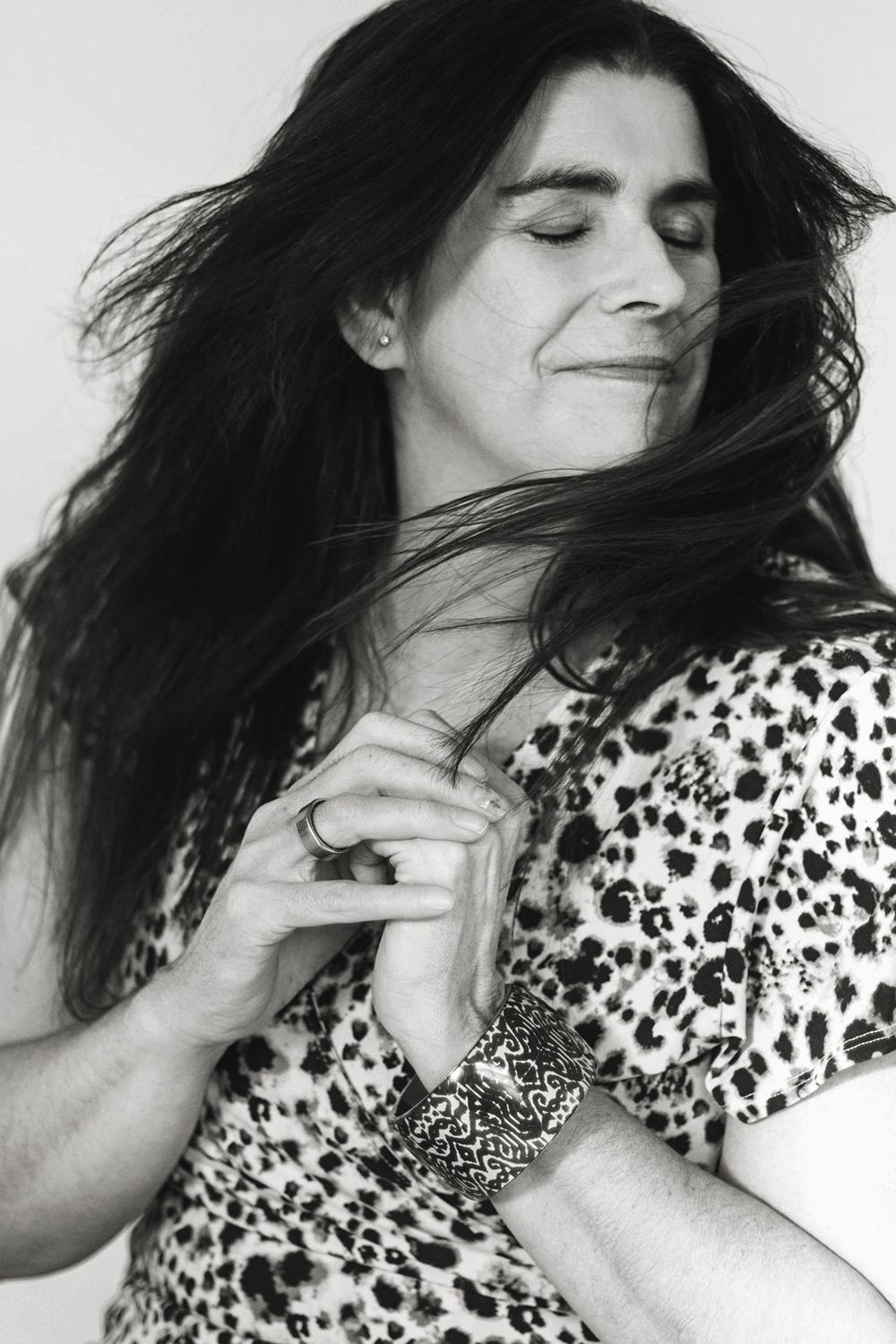 A series of black and white photos showing a person with dark hair in a polka dot top making dynamic movements.