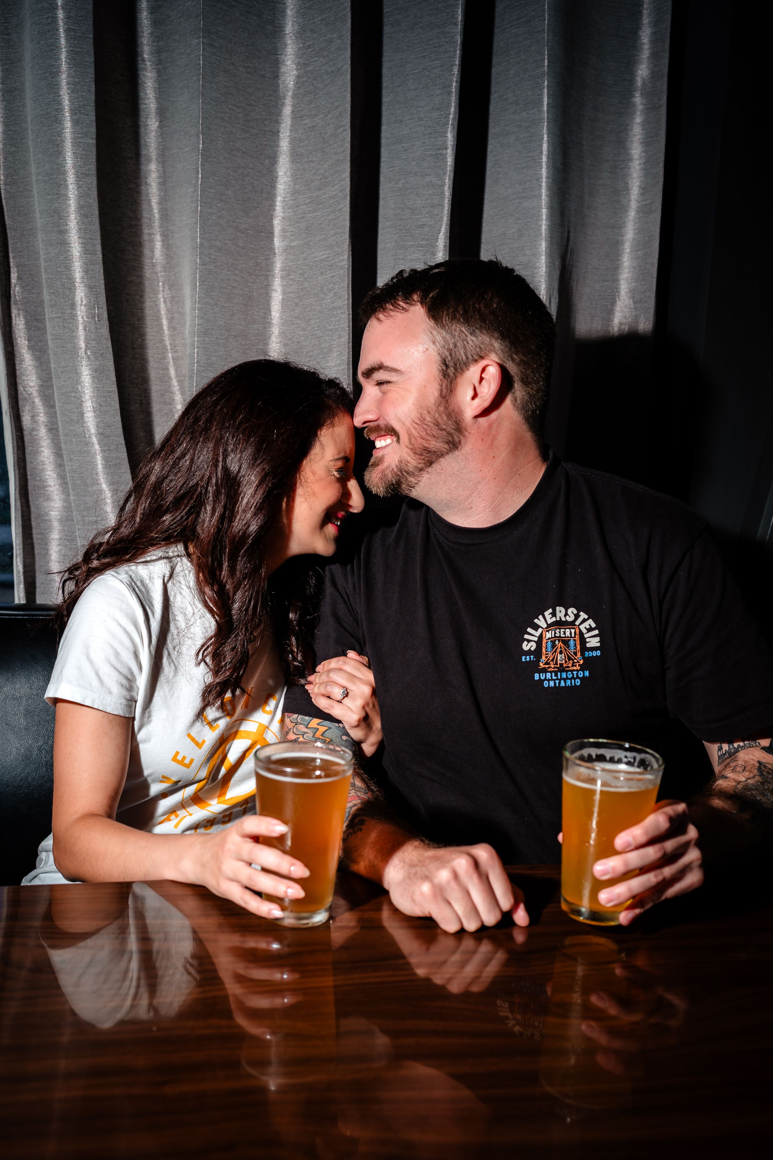 Couple sharing drinks and intimate moment at wooden bar table.