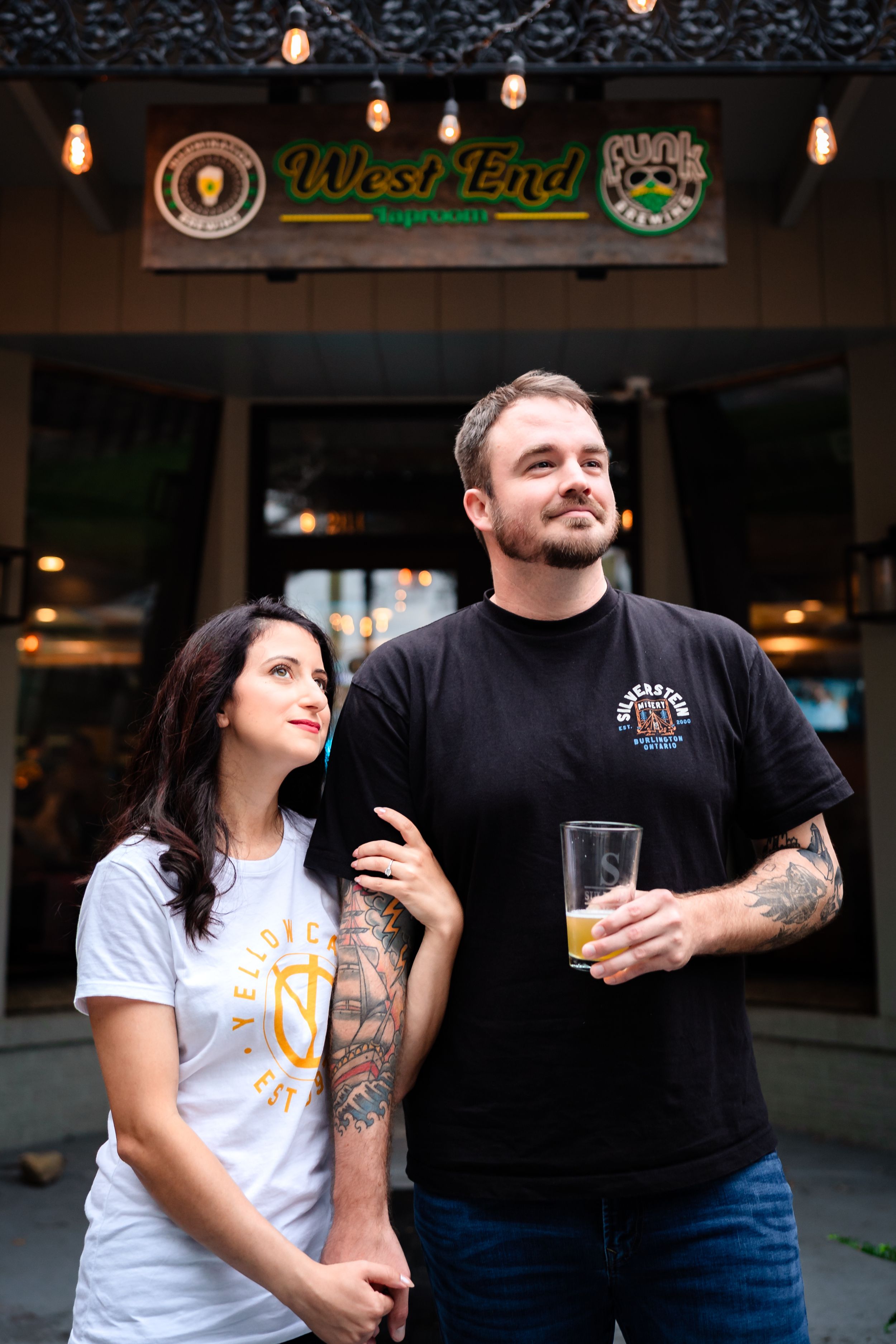 Happy couple sharing drinks and laughter outside a local pub.
