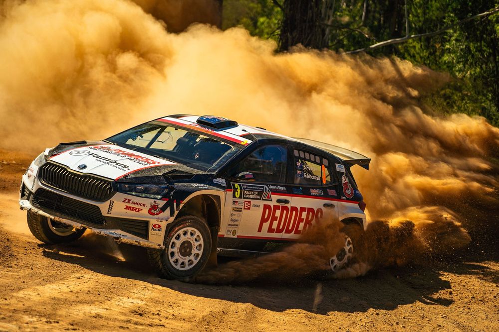 Rally car kicks up dust while racing through a dirt track during intense off-road competition.