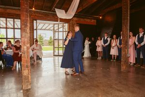 Couple sharing an intimate dance moment in a rustic barn reception venue with exposed wooden beams.