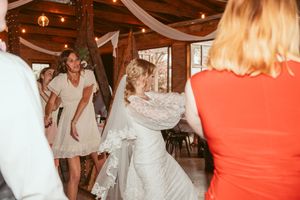Wedding celebration in full swing with dancers moving across a wooden floor under string lights.