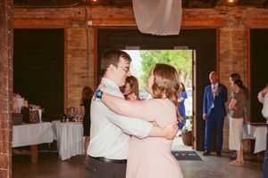 Guests celebrate on the dance floor of a rustic barn venue with exposed brick walls.