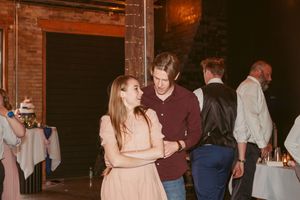 Couples enjoying conversation and mingling at an indoor reception with brick walls and ambient lighting.