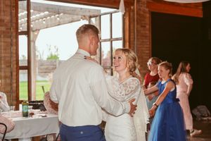 Guests enjoying a lively dance party inside a rustic brick-walled reception venue with decorative lights.