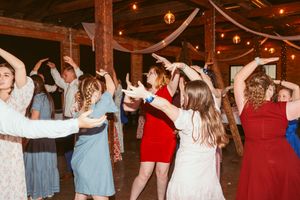Couples dancing on a wooden floor under warm lighting at a barn wedding reception.