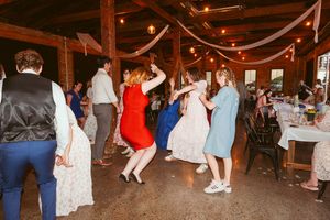 Wedding guests dancing and celebrating on the dance floor at a rustic barn venue.