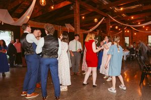 Party guests enjoying themselves on a dance floor in a warmly lit rustic barn setting.