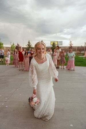 Wedding celebration on outdoor patio with cloudy skies and guests in pink dresses gathered for festivities.