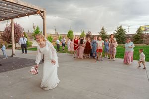 People enjoying an outdoor celebration on a rustic patio with string lights and wooden beams overhead.
