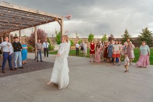 Wedding guests gathered on a large covered patio with cloudy skies and evergreen trees in the background.