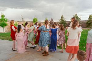 A line of colorful spring dresses walking down an outdoor garden path in a casual group photo formation.