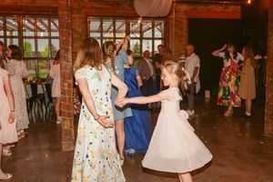 Wedding guests in floral and colorful dresses dancing together on the reception dance floor.