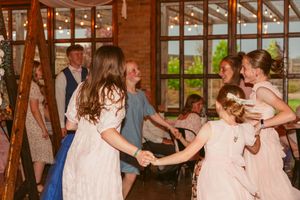 Wedding guests dance together inside a rustic wooden barn venue during a celebration.