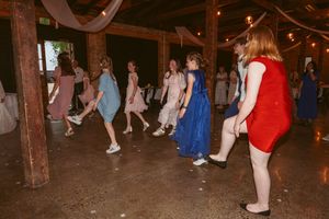 Wedding guests dance on a dark rustic wooden floor during evening reception.