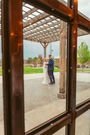 View through wooden pergola frames looking out at an outdoor courtyard with people gathering.