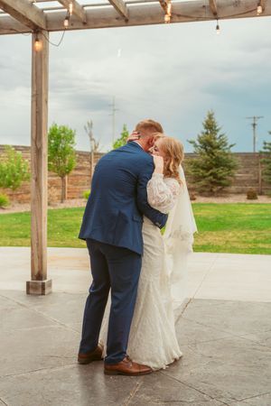 Couple sharing an intimate moment on a patio with rustic wooden beams overhead.