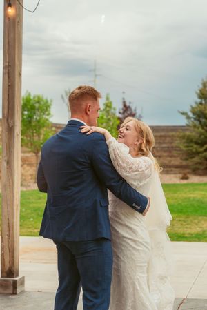 A romantic wedding moment outdoors with the couple sharing a joyful laugh in formal attire.