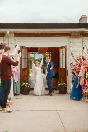 Wedding party celebrates under covered outdoor venue with brick walls.