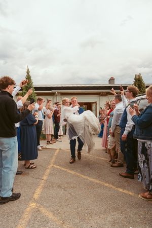 Wedding guests form a receiving line outside venue to celebrate newlyweds.