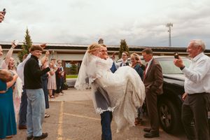 Guests create outdoor celebration corridor at rustic wedding venue.