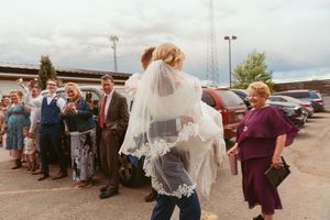 Celebratory wedding guests line up outside to create a walkway for the newlyweds.