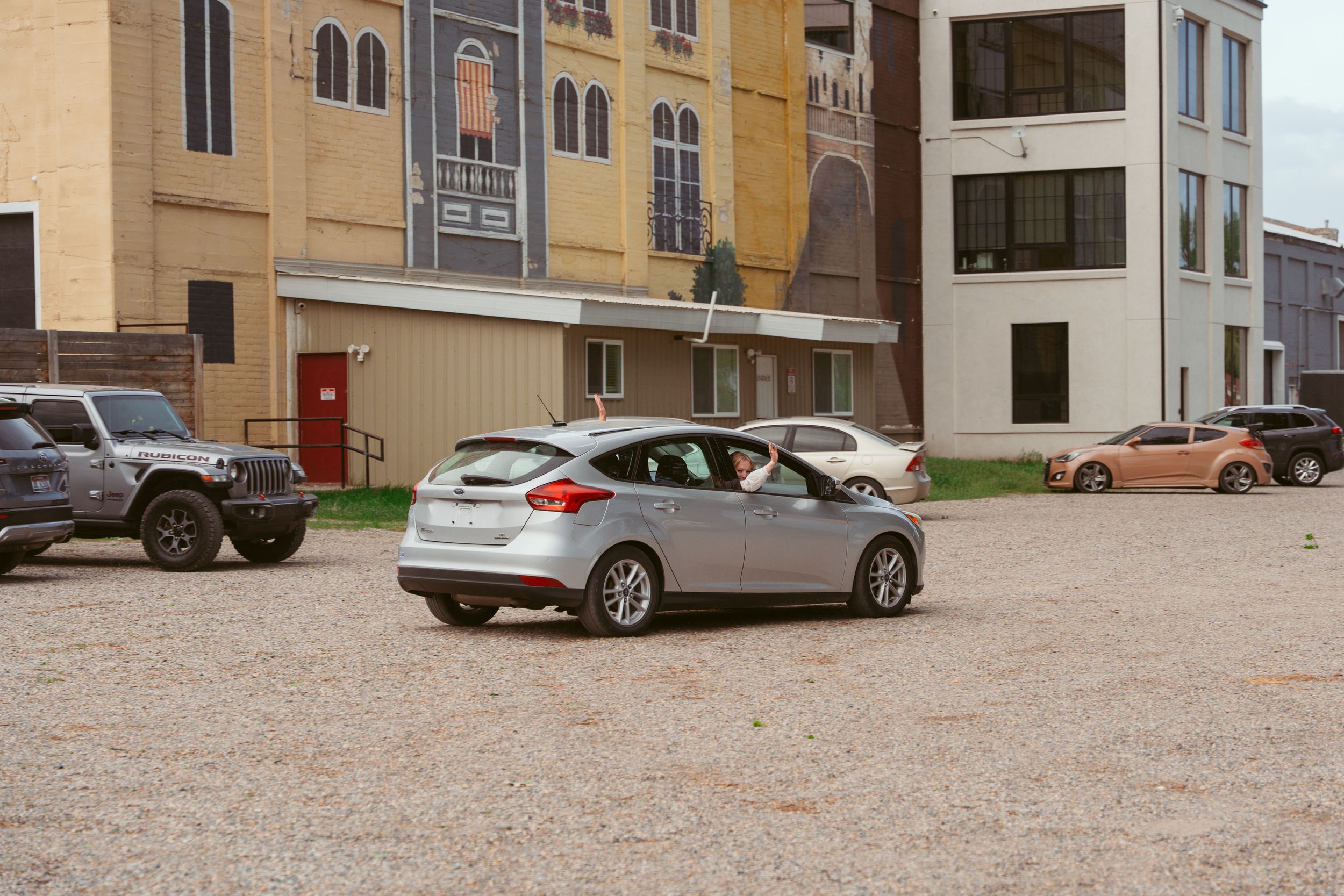 Row of parked cars outside multicolored apartment or condo building.