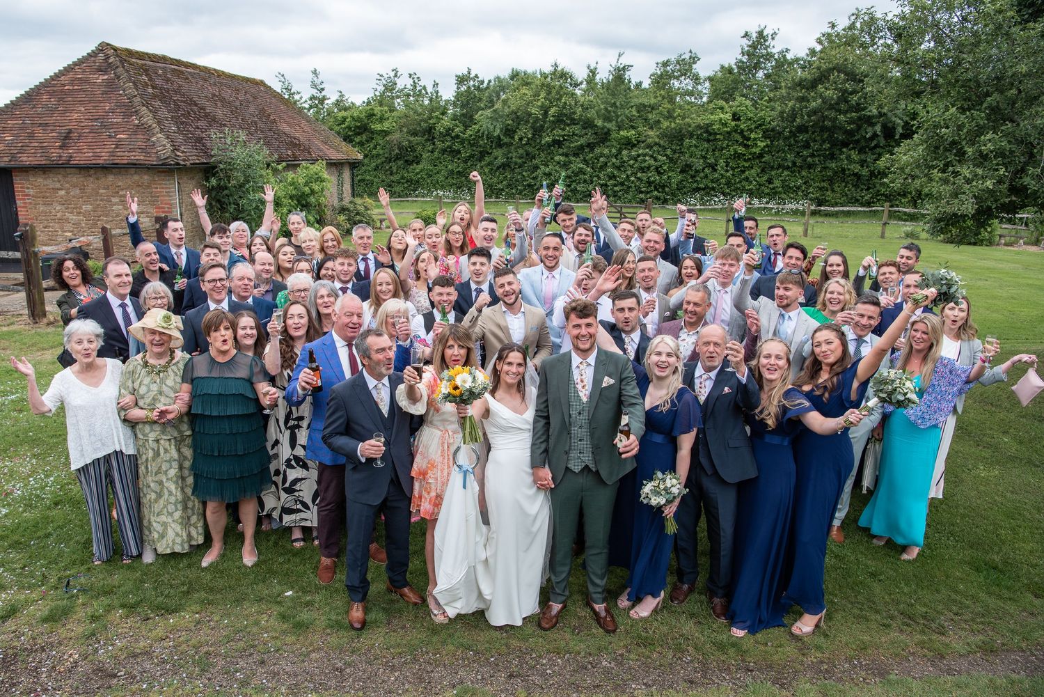 Whole group wedding photo from a height taken in grounds of Clock Barn Hall Surrey