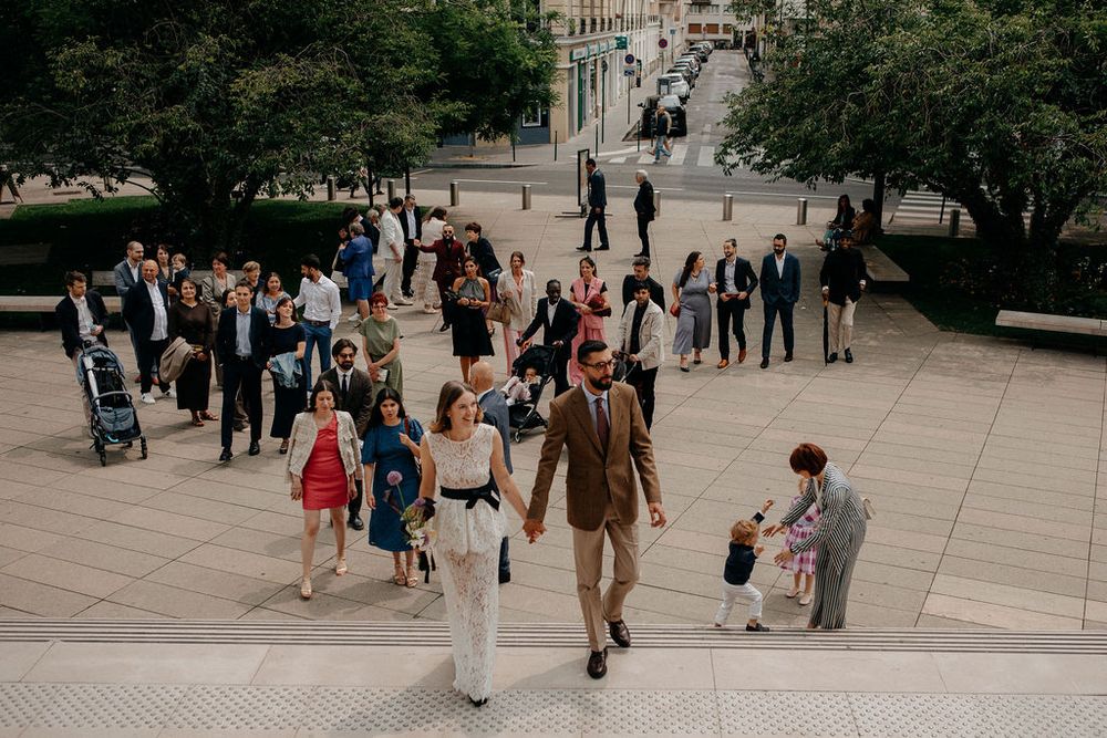 Wedding guests and couple descend outdoor steps at an elegant urban ceremony venue.