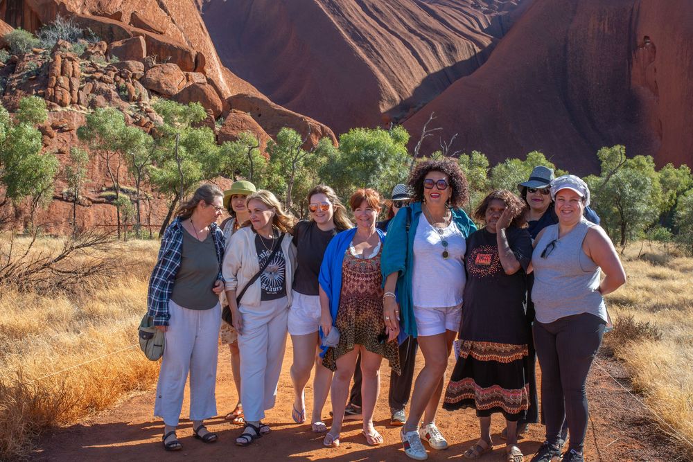 A group of tourists exploring a scenic trail with towering red rock formations at a national park.
