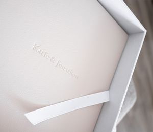 Close-up view of embossed text on white luxury product packaging with raised branding details.