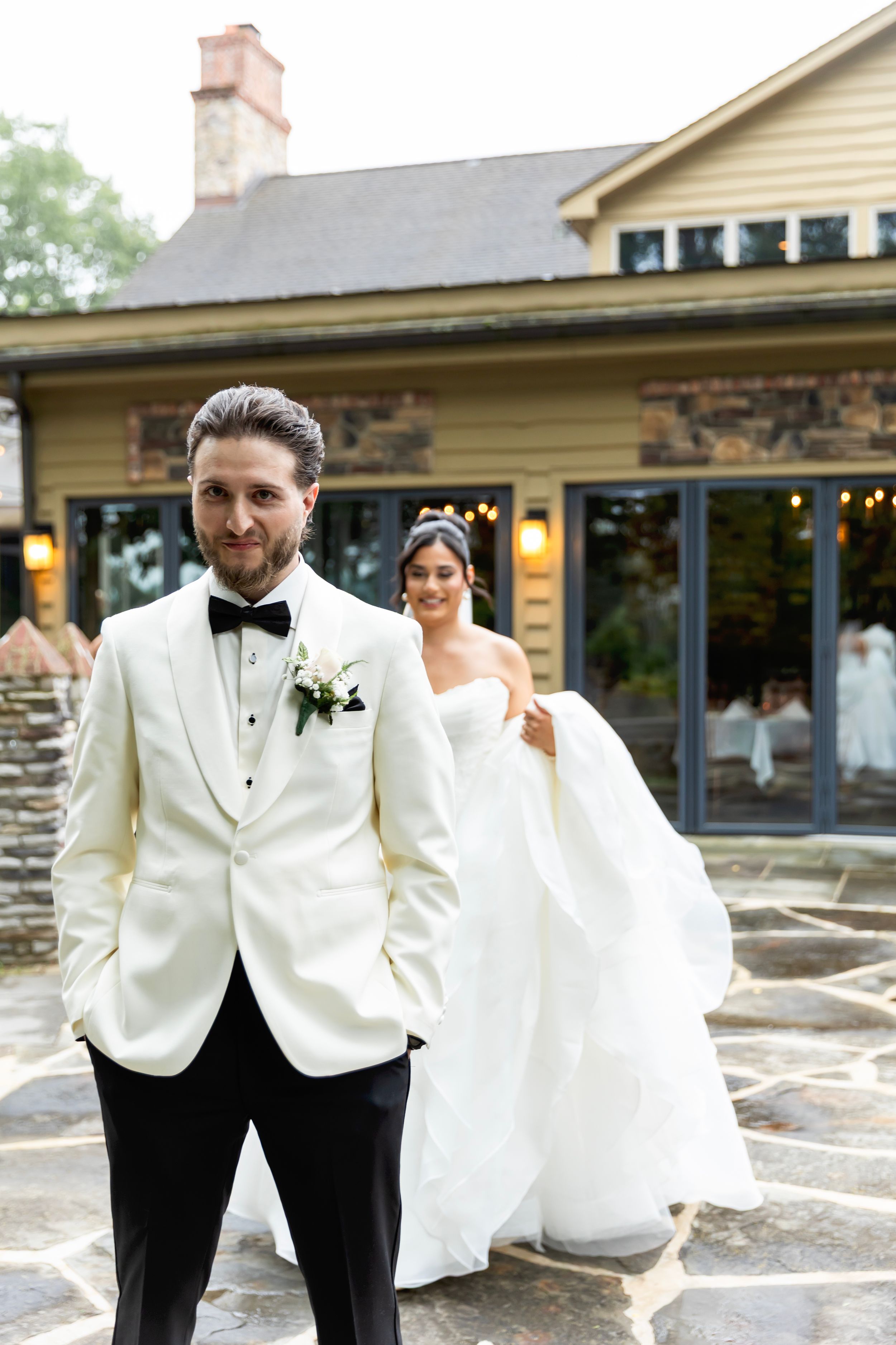 Wedding couple poses together in elegant white and black formal attire during outdoor celebration.