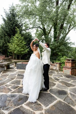 A romantic sequence of a couple dancing on a stone patio surrounded by lush greenery and brick walls.