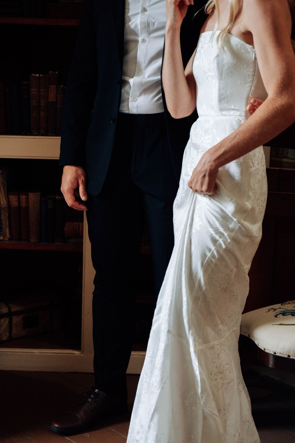 Close-up detail of wedding attire showing white bridal gown and dark suit.