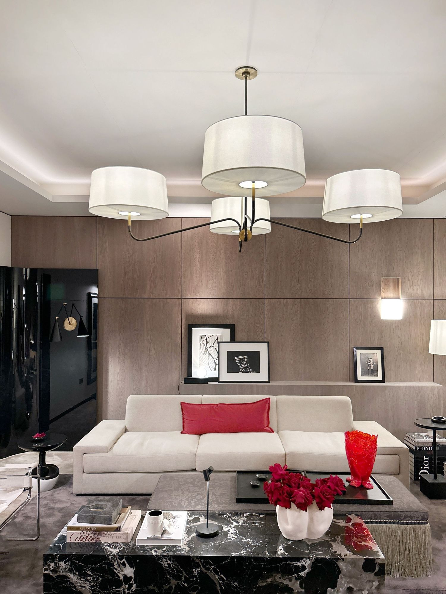 Modern living room with white chandelier, beige sectional sofa, marble coffee table and red accent decor. Kelly Hoppen and Visual Comfort