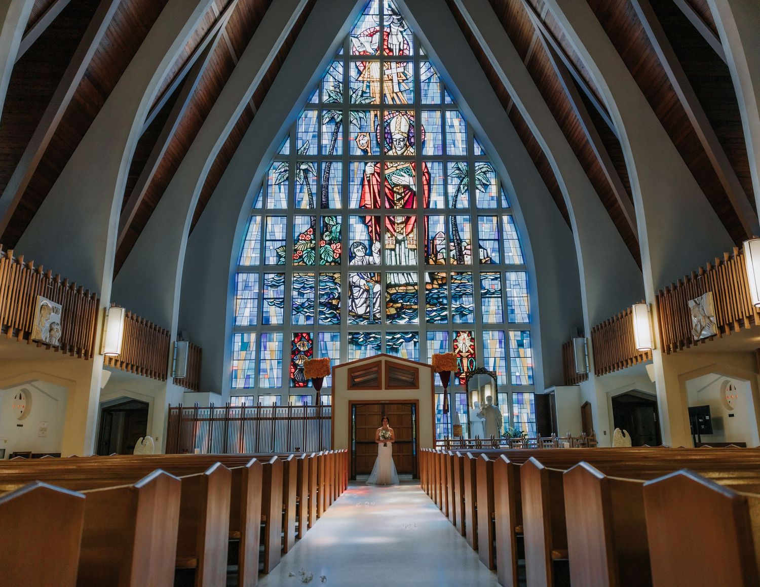 Interior of modern church with dramatic stained glass windows and wooden pews.
