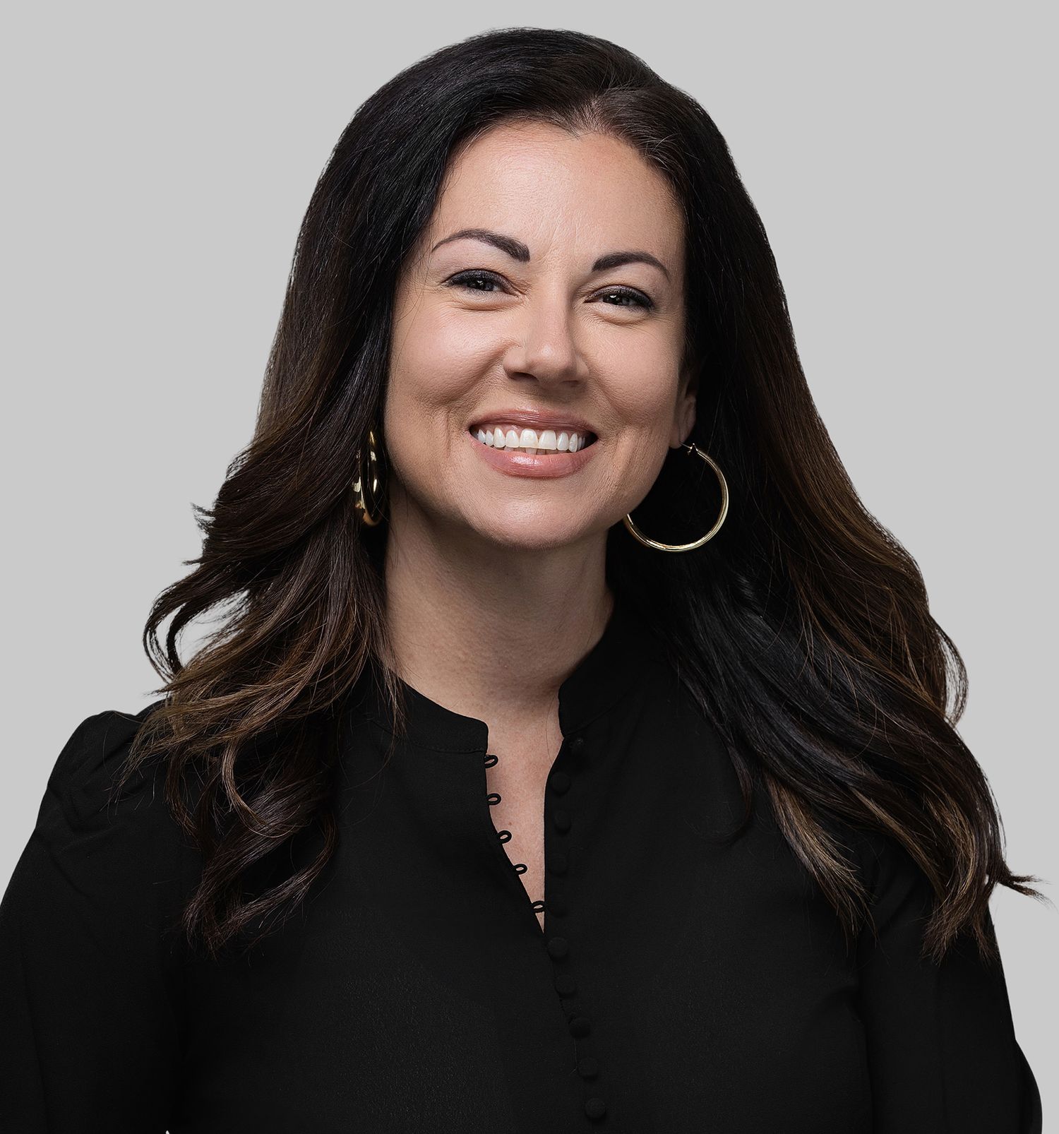 Professional headshot against gray background featuring warm smile and black top.