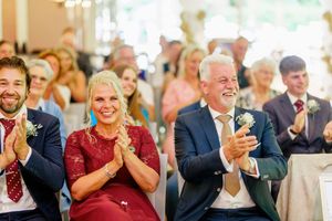 Wedding guests clap and celebrate during a joyful reception in an elegant banquet hall.