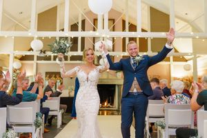 Guests at a wedding reception raise their arms in celebration during a group dance on the dance floor.