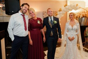 Wedding party guests dance and celebrate together at an indoor reception with warm lighting.