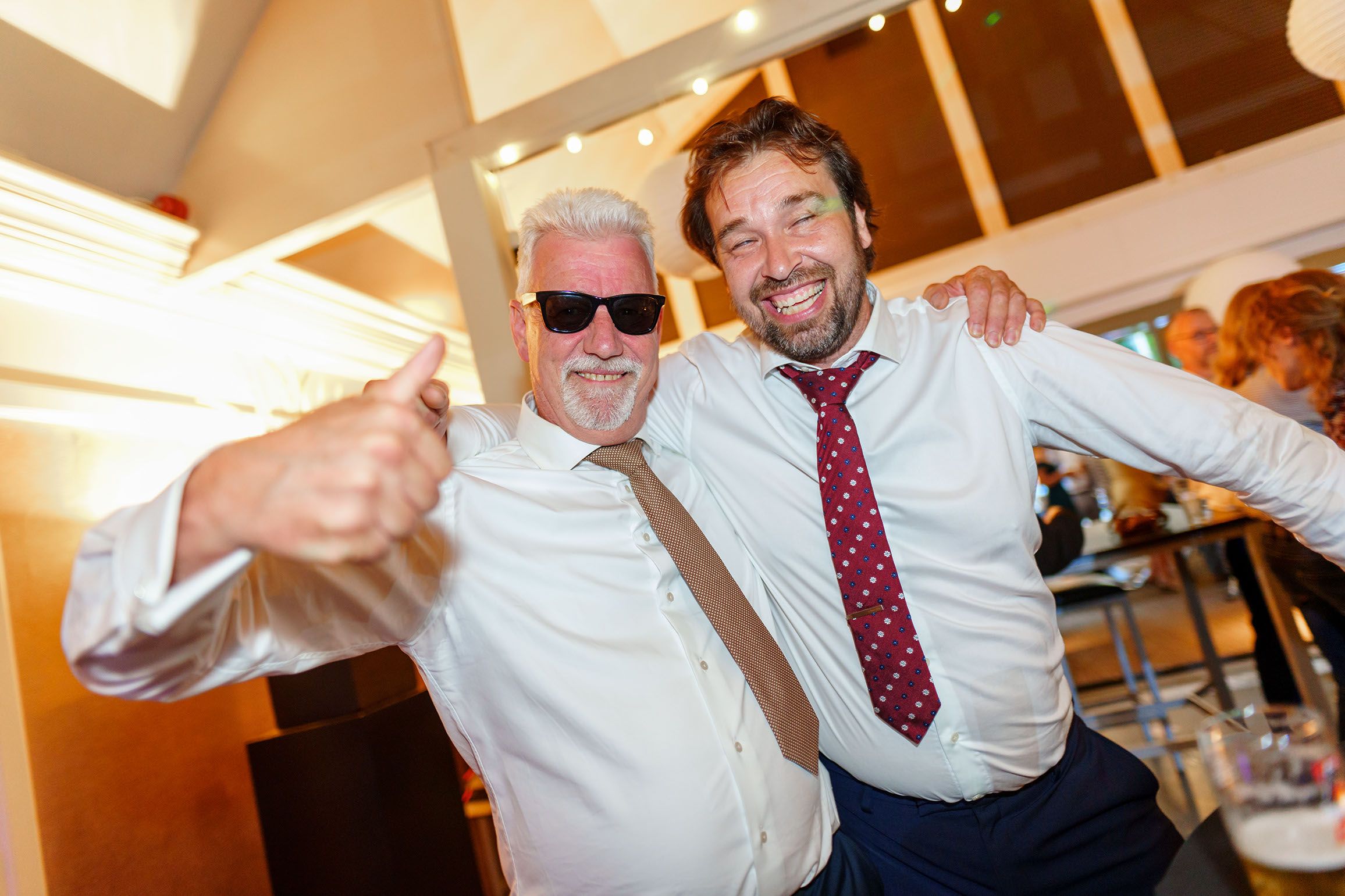 People dancing and celebrating at a wedding reception with arms raised in a joyful moment.