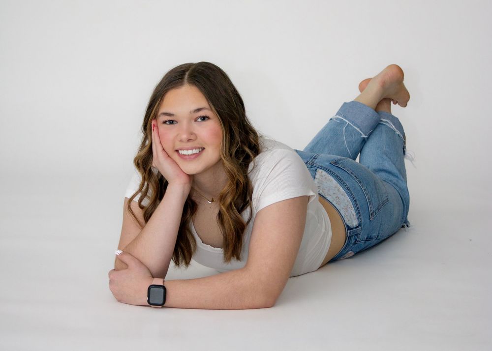 Person wearing white t-shirt and jeans lying on white background in casual poses.