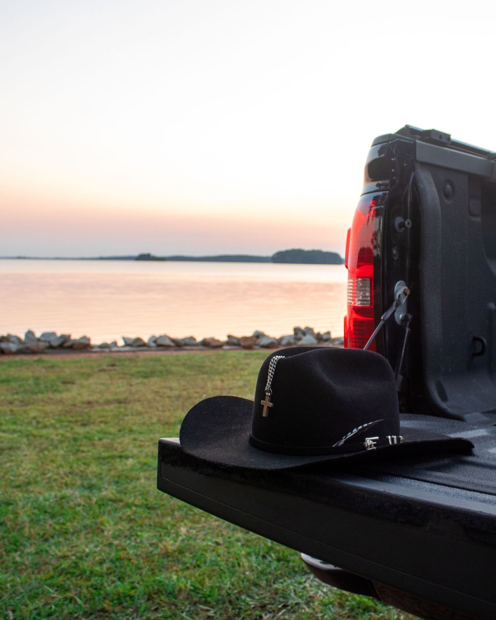 A truck bed pickup liner with a rim light at sunset against a coastal landscape with water in the distance.