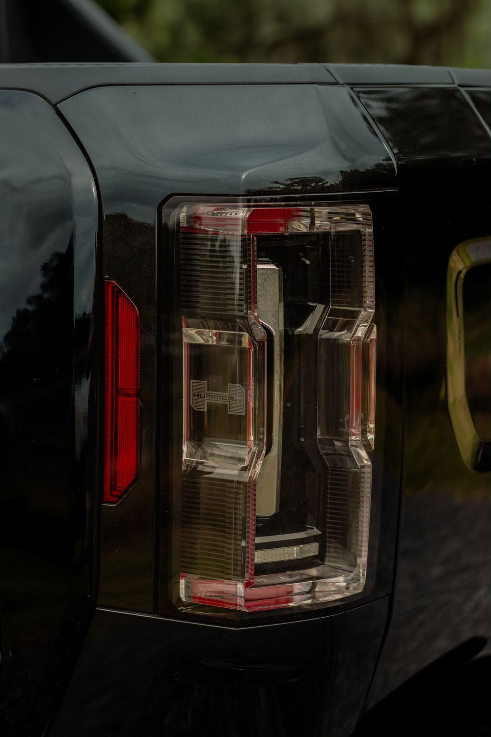 Close-up detail of a modern black vehicle's LED tail light with distinctive C-shaped lighting pattern.