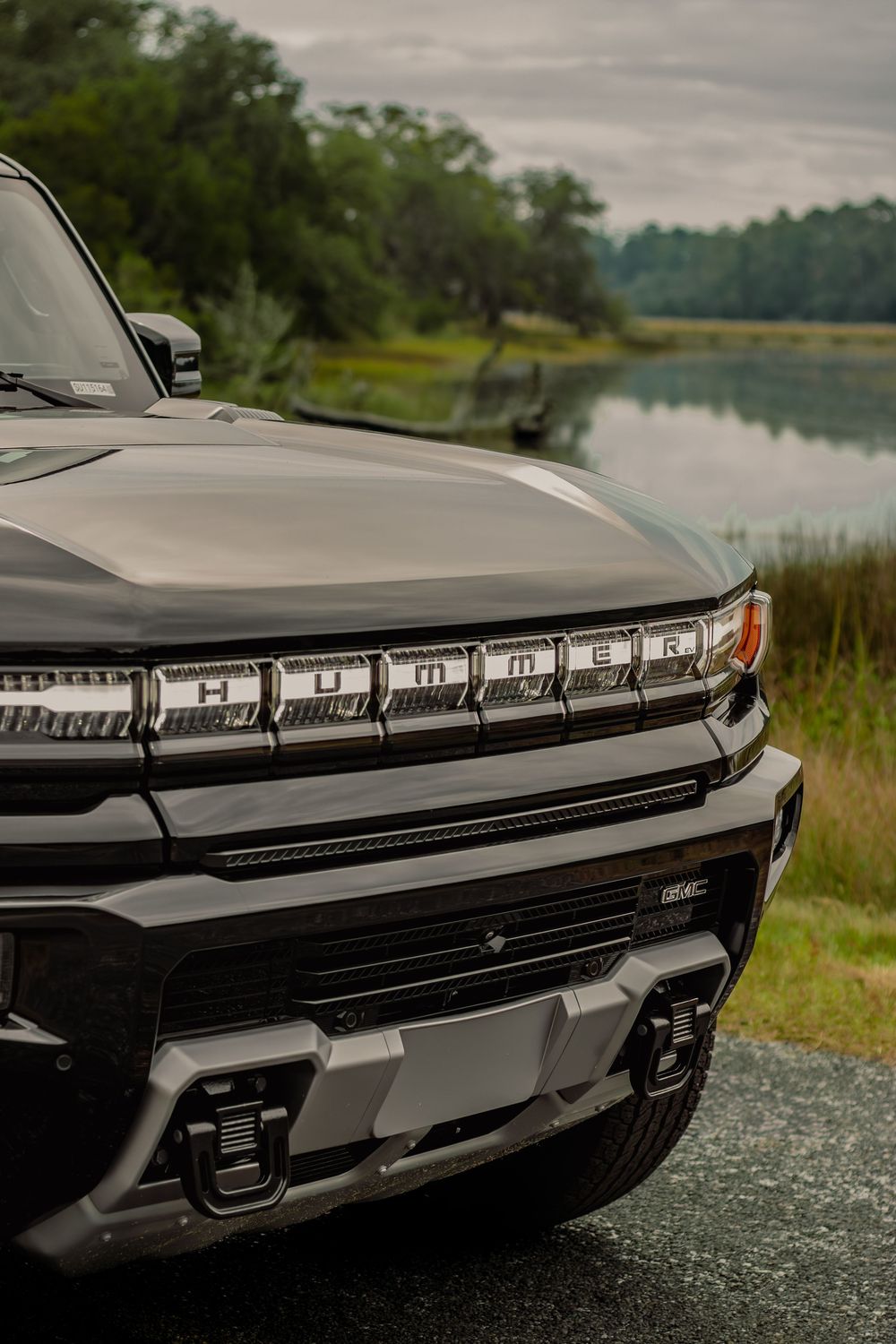 Front end detail of a modern GMC truck showing sleek LED headlights and chrome grille design.